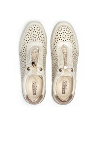 Zapatillas de cuero perforado de color beige claro con suela flexible, que cuentan con un sistema de lazada elástica central y detalles en marrón.