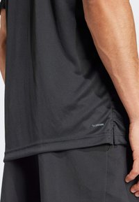 Camiseta deportiva negra de tejido liso y ligero con un sutil brillo. Incluye el logo "Climacool" cerca del dobladillo y un corte holgado.