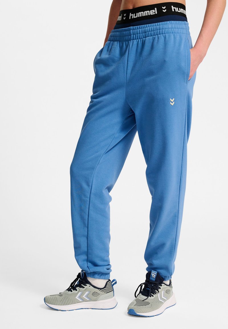 Blå sweatpants med en afslappet pasform, der har sidelommer, et sort elastisk taljebånd med logo og smalle ben.