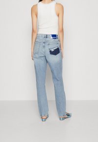 Světle modré džínové kalhoty s pohodlným střihem, s kontrastními kapsami a značkovou nášivkou na zadním pásku. Hladká textura, rovné nohavice.