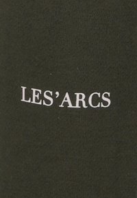 Donkergroene stof met een gladde textuur, voorzien van witte tekst die "LES'ARCS" in een eenvoudig, modern lettertype leest.