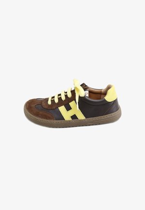 Zapatilla baja con ante marrón, cuero negro, cordones amarillos, lengüeta en el talón y logotipo lateral "H", con suela de goma texturizada.