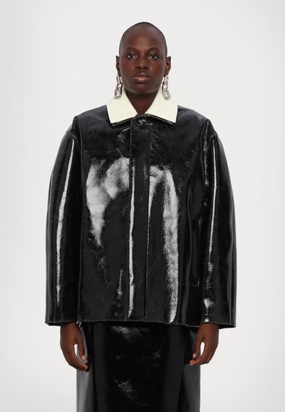 Giacca in pelle verniciata nera con colletto bianco, vestibilità oversize, chiusura frontale a bottoni e superficie liscia e lucida.
