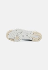 Suola di scarpa da ginnastica bianca con gomma testurizzata, caratterizzata da un motivo geometrico e un accento circolare al centro. Design durevole e flessibile.