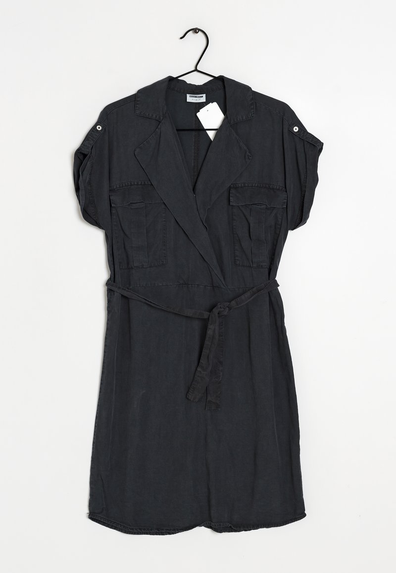Robe courte gris foncé à manches courtes avec ceinture, col, deux poches poitrine avant et pattes de manches boutonnées, suspendue sur un cintre noir sur fond blanc.