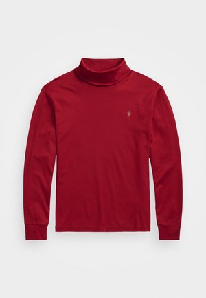 Crvena turtleneck majica dugih rukava izrađena od glatkog materijala s uskim krojem. Ima mali zlatni logo na lijevoj strani prsnog dijela.