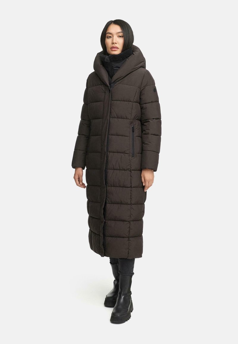 Lång mörkbrun pufferjacka med huva, som har en kviltad design, sidofickor och en figurnära silhuett. Mjuk material och texturerad yta.