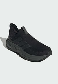 Čierne športové slip-on topánky s textúrovaným pleteným zvrškom, gumovou podrážkou a tromi tmavými pruhmi na boku. Ľahký a flexibilný dizajn.