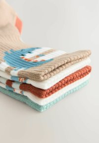Cinque paia di calze di lana impilate. I colori includono beige, bianco, arancione e teal. Presenta un design di pupazzo di neve sulla calza beige. Texture morbida.