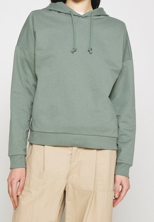 Felpa verde in cotone con cappuccio regolabile, vestibilità morbida, polsini e orlo ribattuti. Design semplice senza motivi o loghi visibili.
