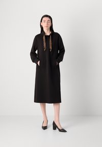 Must have dress, mille kasutatud kappi juurde. Must kleit kapuutsiga, leopardimustriga tõmblukud, pikad varrukad ja küljetaskud. Kantud koos mustade kõrgete kontsadega.