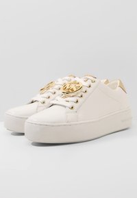 Sneakers in pelle bianca con dettagli dorati, logo rotondo sulla linguetta e suola platform. Texture liscia e design minimalista.
