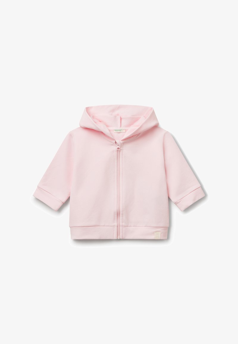 Světle růžová mikina na zip vyrobená z měkké látky. Má kapuci, krátké rukávy a malou logovou nášivku na lemu. Jednoduchý a minimalistický design.