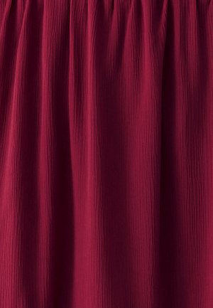 Tessuto borgogna con un aspetto testurizzato e spiegazzato, raccolto nella parte superiore, creando sottili linee verticali su tutto il materiale.