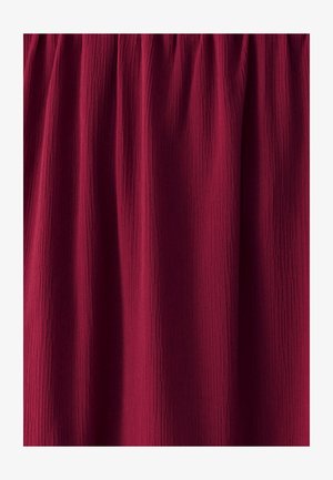 Tessuto borgogna con un aspetto testurizzato e spiegazzato, raccolto nella parte superiore, creando sottili linee verticali su tutto il materiale.