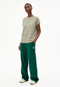 T-shirt à manches courtes vert clair associé à un pantalon de survêtement vert avec un détail en ruban. La tenue a une coupe décontractée et une texture de tissu douce.