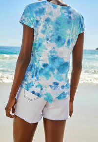 Lyhythihainen t-paita sinivalkoisessa sitruunapainannassa, jossa on raidallinen kuosi; yhdistettynä valkoisiin, reikäisiin shorts-eihin, joissa on rento istuvuus.