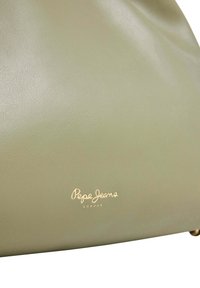 Bolso de mano de cuero verde con una textura suave, que presenta un detalle del logo dorado en la parte inferior. Diseño sencillo, forma suave y hardware mínimo.