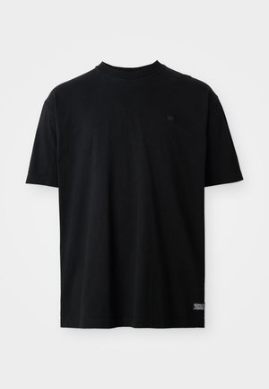 Tricou negru din bumbac, cu mâneci scurte și decolteu rotund. Are un logo mic pe piept și o etichetă pe marginea de jos.