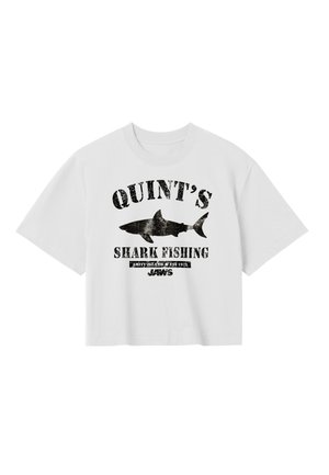 Camiseta blanca recortada con texto gráfico negro que dice "QUINT'S SHARK FISHING" junto a una silueta negra de un tiburón y la palabra "JAWS" debajo.