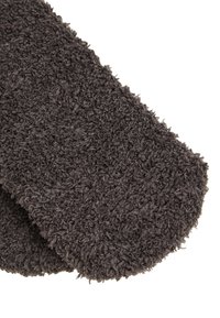 Coperta in pile di un grigio scuro, morbida e di peluche, con una superficie testurizzata e un bordo leggermente arrotondato. Il tessuto appare spesso e accogliente.