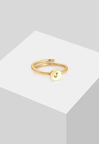 Guld ring med et åbent design, der har en cirkulær skive stemplet med bogstavet "J." Glat overflade og minimalistisk stil.