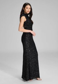 Mustapintainen paljettimekko, jossa on korkea kaula-aukko, olkapäälä ja vartalonmyötäinen siluetti. Lattiaa hipova malli, jossa on hienovarainen kimalle ja sivuaukko.