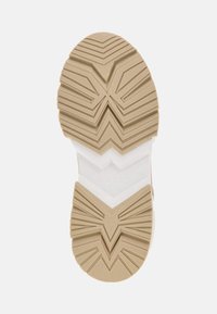 Beige kummist jalanõu välistald, millel on siksakmustrid. Omab valget vahetald ja embosseeritud logo detaili, pakkudes haarduvust ja tuge.