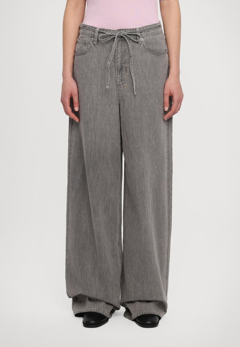 Wide-leg gray denim trousers with a drawstring waist, side pockets, and a relaxed fit. Smooth texture with minimal stitching details.