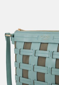 Vävd handväska i ljusblått konstläder med tan-färgade tygdetaljer, med dragkedjestängning och guldtonade detaljer.