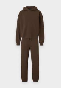 Καφέ φούτερ με κουκούλα και αντίστοιχο παντελόνι φόρμας με κορδόνι στη μέση και τελειώματα στα μανσέτα, σε λευκό φόντο.