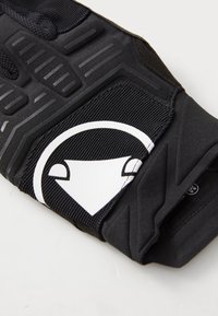 Zwarte fiets handschoen met een gestructureerde grip, gevoerde delen en een wit logo op de pols. Materiaal lijkt synthetisch en flexibel te zijn.