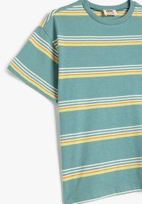 Camiseta de algodón en color verde azulado con mangas cortas, con rayas horizontales en blanco, amarillo y naranja. Textura suave con diseño de cuello redondo.