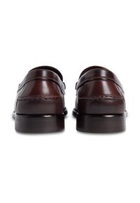 Καφέ δερμάτινα μοκασίνια με λείο φινίρισμα, που διαθέτουν έντονη ραφή και χαμηλό τακούνι για ένα κλασικό σχέδιο.