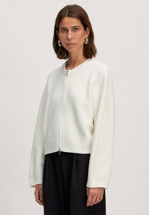 Witte geribbelde zip-up trui, cropped ontwerp, ronde halslijn, verlaagde schouders en textuurstof. Gecombineerd met een zwarte onderkant.