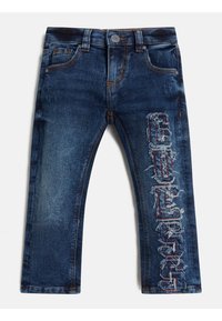 Jeans de mezclilla azul oscuro con un diseño desgastado y el logo bordado "GUESS" en la pierna izquierda, con un estilo estándar de cinco bolsillos.