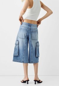 Farkku culotte-shortsit vaaleansinisinä, joissa on kaksi suurta sivutaskua, takataskut ja löysä istuvuus keskikorkealla vyötäröllä.