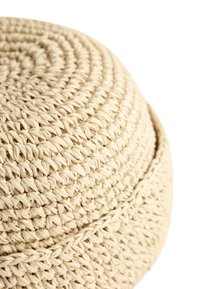 Gros plan d'un chapeau de paille tressée beige montrant des motifs détaillés en spirale et tressés sur la calotte et le bord.