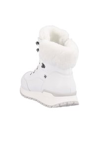 Bottes de randonnée blanches avec une cheville doublée de fourrure, tige en cuir, œillets noirs proéminents et semelle en caoutchouc texturée pour une meilleure adhérence.