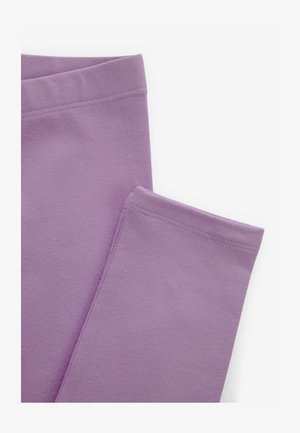 Primo piano di leggings di cotone lavanda piegati che mostrano la vita e gli orli cuciti su uno sfondo bianco semplice.