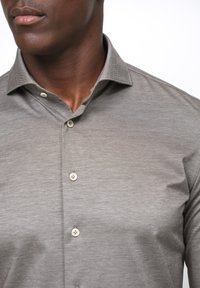 Grijze button-up shirt gemaakt van gladde stof, met een gestructureerde kraag, subtiele textuur en vier lichtgekleurde knopen aan de voorkant.