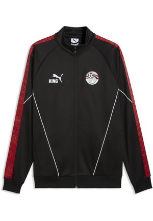 Sort sportstrøje med lynlås med røde geometriske striber på ærmerne, hvide partier, Puma og King logoer og Egyptiske fodboldforenings emblem på brystet.