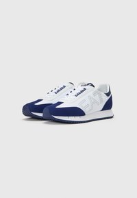White and navy sneakers with a smooth leather and suede upper, featuring a prominent logo, lace-up design, and textured rubber sole.
