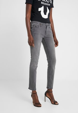 Grijze denim skinny jeans met een middelhoge taille, voorzakken en lichte slijtage details. Gecombineerd met een zwart t-shirt en zwarte spijkerhakken.
