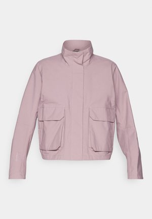 Chaqueta exterior de color rosa claro con cuello alto, dos grandes bolsillos frontales y mangas largas. Textura suave con detalles de costura visibles.