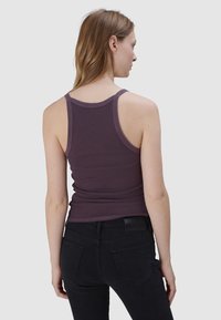 Paarse geribbelde tanktop met een getailleerd ontwerp, brede bandjes en een ronde rug, gecombineerd met zwarte slim-fit jeans.