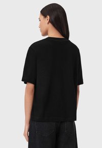 Μαύρο βαμβακερό t-shirt με κοντά μανίκια και άνετη εφαρμογή. Διαθέτει λαιμόκοψη και διακριτικές ραφές. Φοριέται με σκούρο τζιν.