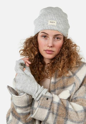 Gray ribbed beanie with a logo patch, worn with light gray fingerless gloves, paired with a plaid wool coat in beige and gray tones.