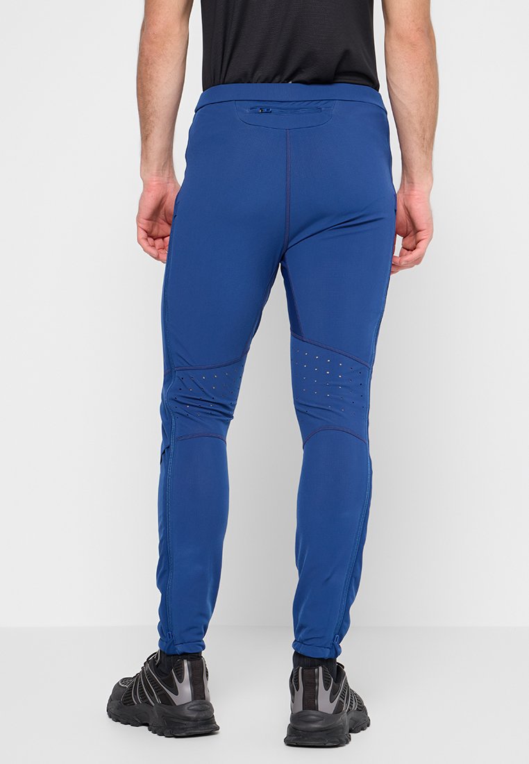 Niebieskie spodnie sportowe o dopasowanym kroju, z teksturowanej tkaniny, panelami z siateczki i akcentującym przeszyciem. Zawierają odblaskowe detale i kieszeń w pasek.