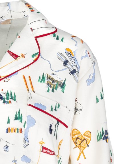 Parte superior de pijama blanca con estampados multicolores de temática al aire libre, con ribetes rojos en el cuello y el bolsillo. El material parece suave y ligero.